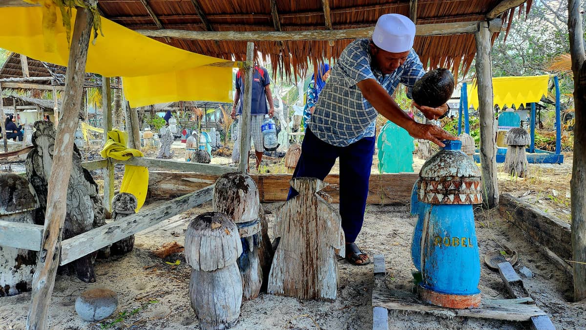 The ritual washing of the sunduk or grave marker with water using a coconut shell.